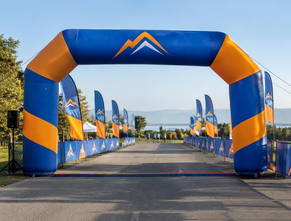 Branded inflatable arch over a race start with feather flags lining the course